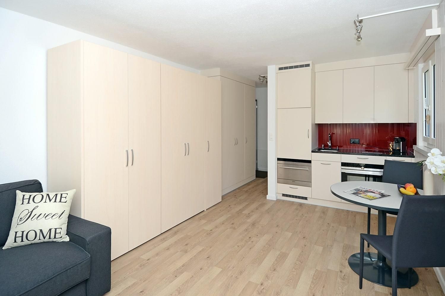 Wohnbereich mit Tisch, Küche und Wandschrankbett - Ferienwohnung Studio 25 - Haus Green - Davos Platz